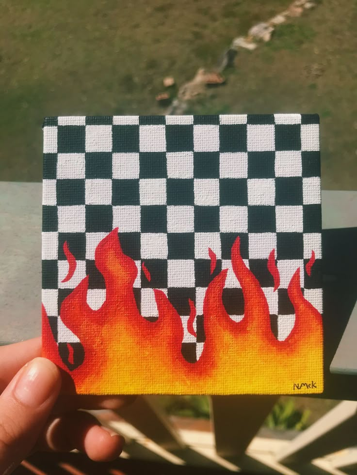 a hand holding up a piece of art with flames on it's back side