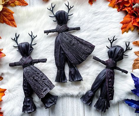 three black figurines with antlers on top of a white fur covered surface