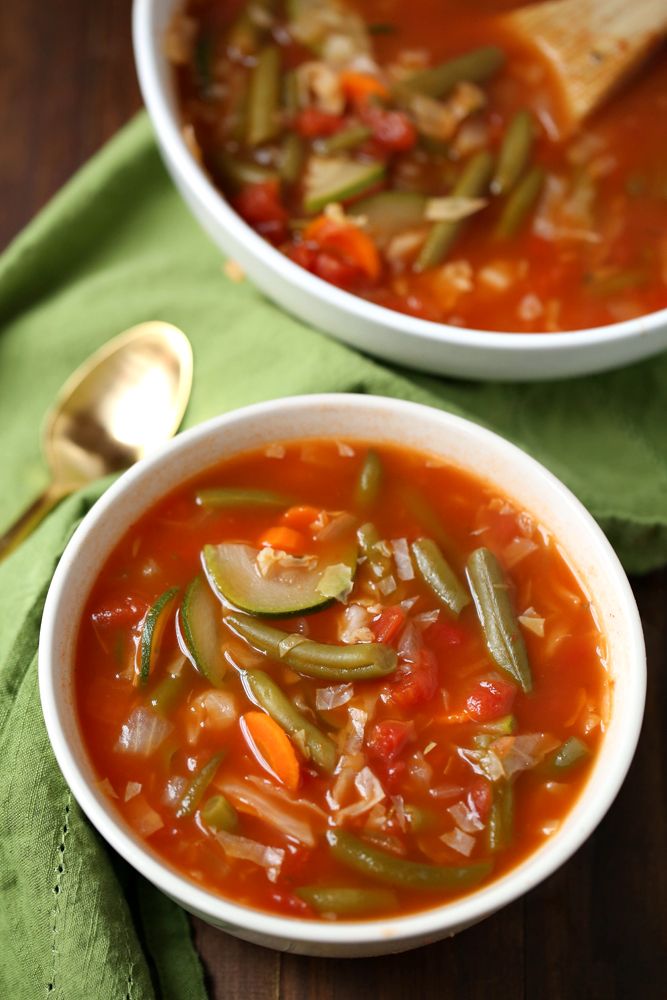 two bowls filled with soup on top of a green cloth next to a spoon and napkin