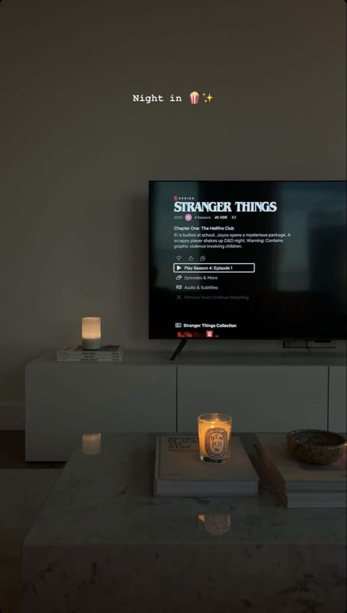 a television sitting on top of a white table next to a candle and remote control