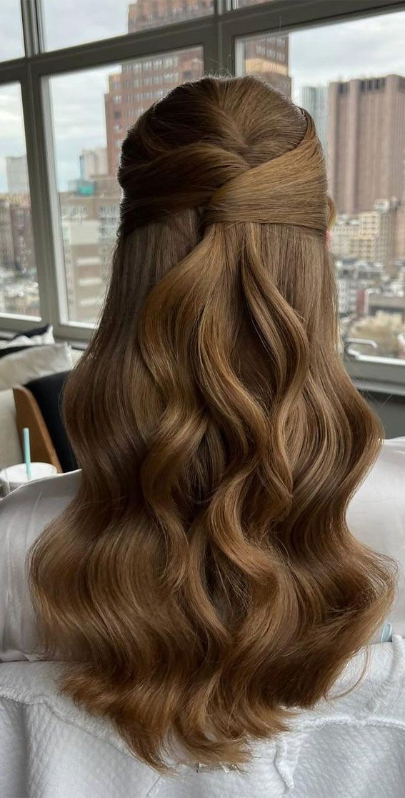 the back of a woman's head with long wavy hair in front of a window