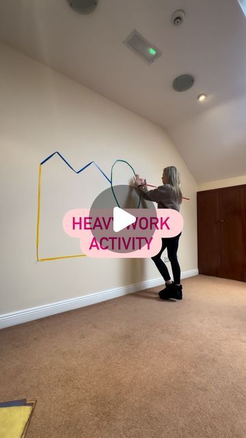 a woman standing in an empty room with a sign that says heavy work activity on the wall