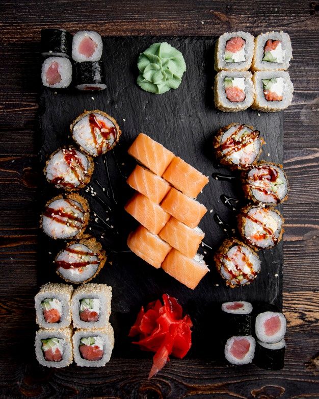 sushi is arranged on a slate board with chopsticks and garnishes