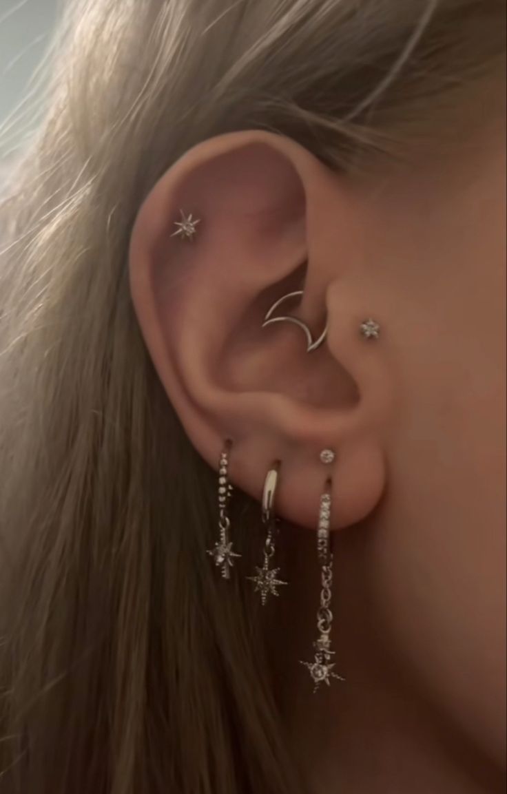 a close up of a person with ear piercings and stars on their left side