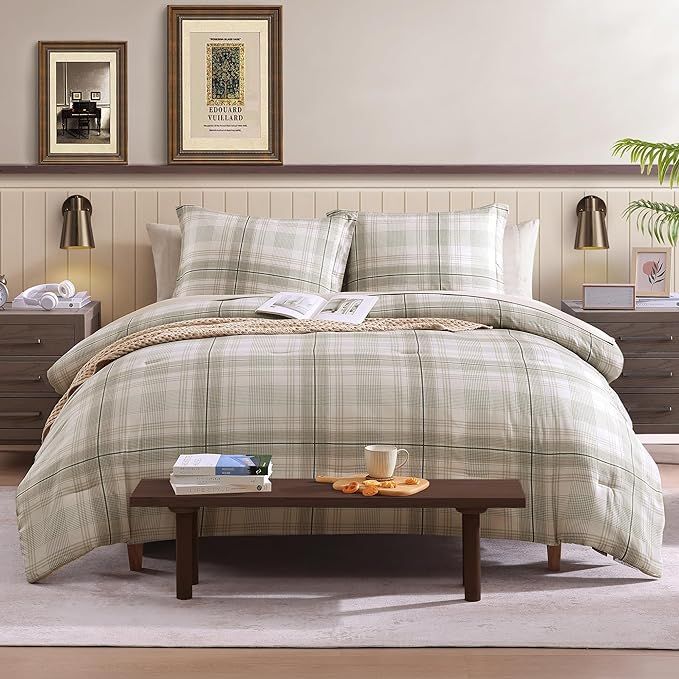 a bed with plaid comforter and pillows in a room next to two framed pictures