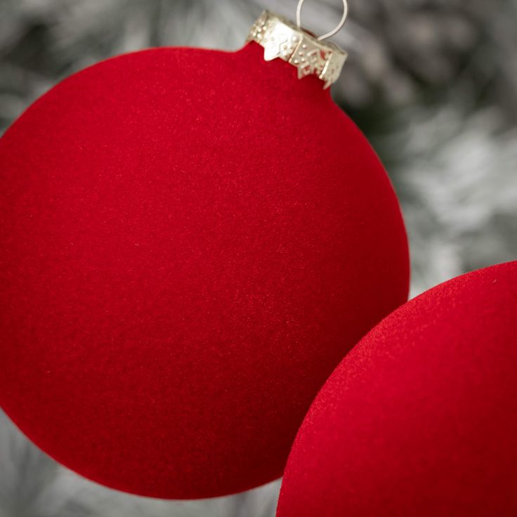 two red ornaments hanging from a christmas tree