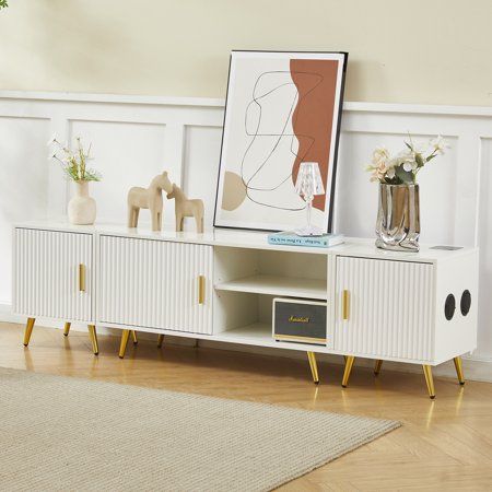 a white entertainment center with art on the top and two vases filled with flowers