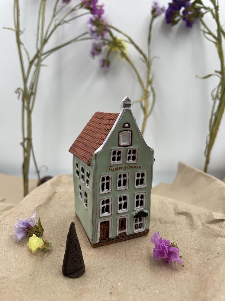 a small house sitting on top of sand next to flowers