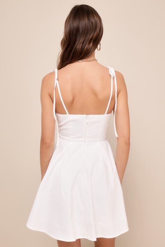 Bask in the sunshine (and compliments) in the Lulus Breezy Aura Ivory Tie-Strap Mini Skater Dress! This summery dress has a lightweight cotton-blend stretch-woven composition that falls from tying straps into a sweetheart neckline and a seamed bodice. High, fitted waist sits atop a twirl-worthy skater skirt that ends at a flirty mini hem. Hidden back zipper/clasp. Fit: This garment fits true to size. Length: Mid-thigh. Size medium measures 26" from adjustable straps to hem. Bust: Great for any c Cotton A-line Dress With Adjustable Straps, White A-line Sundress With Tie Straps, White A-line Mini Dress With Adjustable Straps, Summer Cotton Sundress With Knotted Straps, Spring Cotton Mini Suspender Dress, Spring Cotton Suspender Dress In Mini Length, Cotton Suspender Dress, Mini Length For Spring, White V-neck Mini Dress With Tie Straps, Spring Mini Cotton Suspender Dress