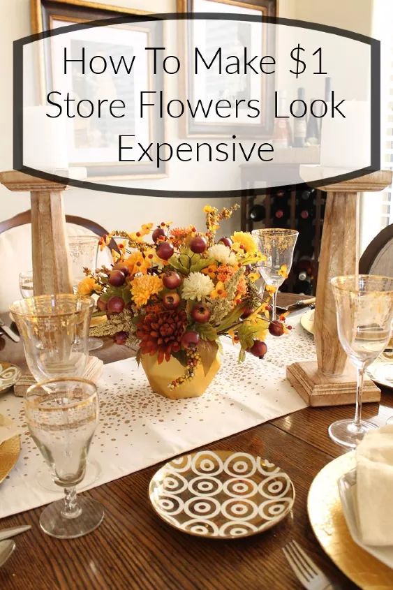 a dining room table with flowers in a vase and wine glasses on the placemat