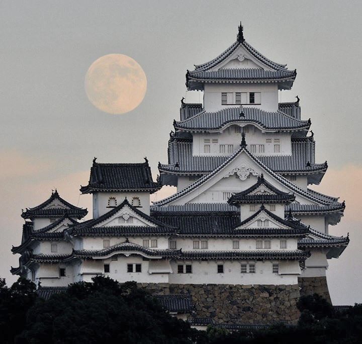 the moon is setting behind an old castle