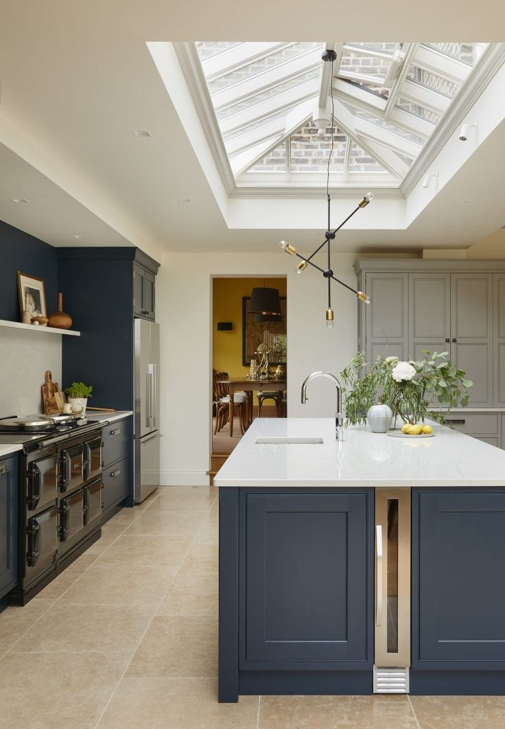 a large kitchen with an island and skylight in the ceiling, along with blue cabinets