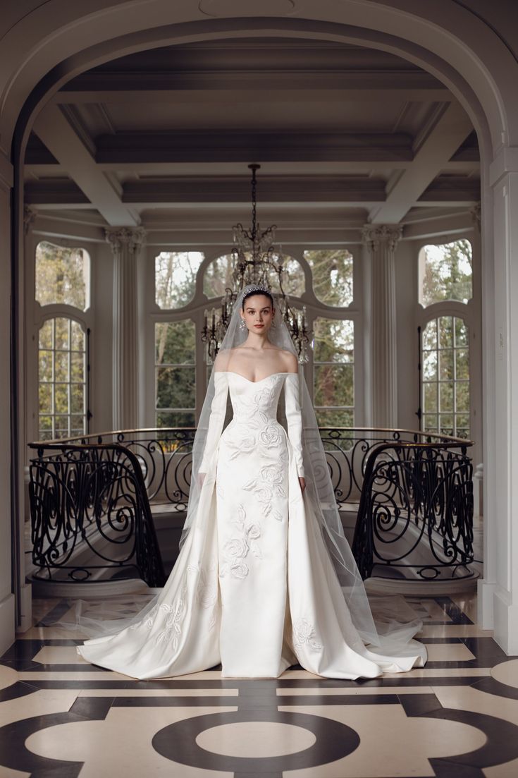 a woman in a white wedding dress standing on a black and white floor with a chandelier