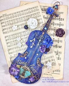 a blue violin keychain with music notes and flowers on it's side