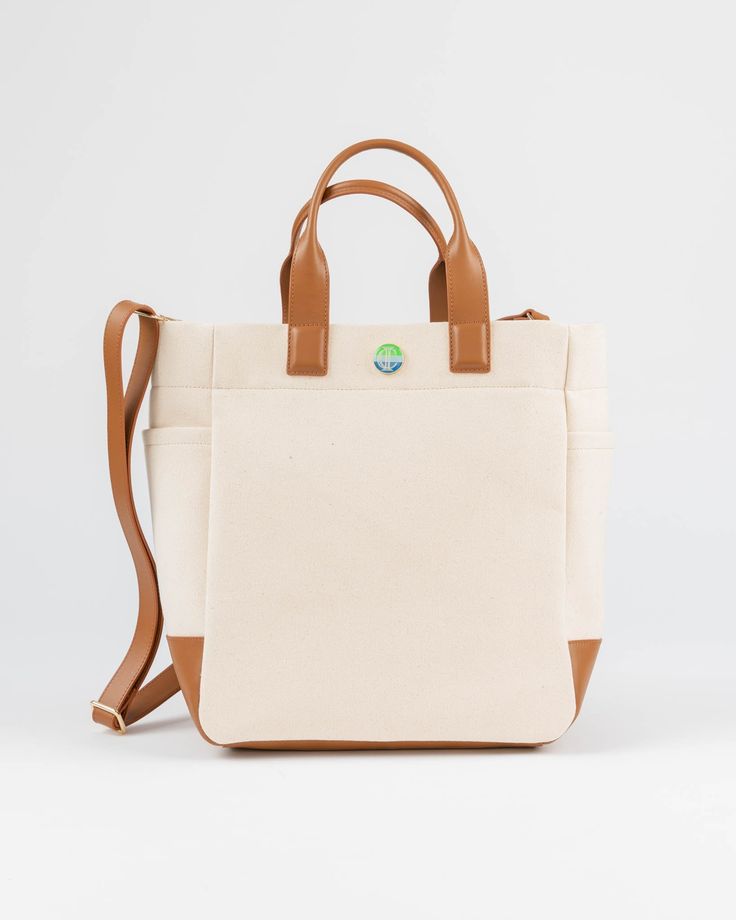 The Cape Code Tote is a truly elevated and refined take on the classic design. The design featured dual handles and a detachable strap for convenience. The spacious interior will fit all your daily needs and even works as a weekender or picnic bag. The streamlined style complements any outfit and works for his, hers, and theirs. • Natural/Saddle • 100% cotton with leather trim • Unlined • Two exterior side pockets • Leather bottom • Detachable & adjustable strap • 6” handle drop • Measures 11.5” Travel Weekender Bag With Coated Canvas Handles, Functional Satchel With Detachable Handle For Daily Use, Beige Weekender Bag For On-the-go, Coated Canvas Weekender Bag With Adjustable Strap, Modern Travel Bag With Handles For On-the-go, Beige Top Handle Weekender Bag, Luxury Travel Canvas Bag With Double Handle, Canvas Travel Bag With Top Carry Handle, Luxury Canvas Bag With Double Handle For Travel