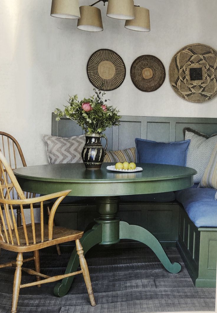 a table with two chairs and a bench in front of some pictures on the wall