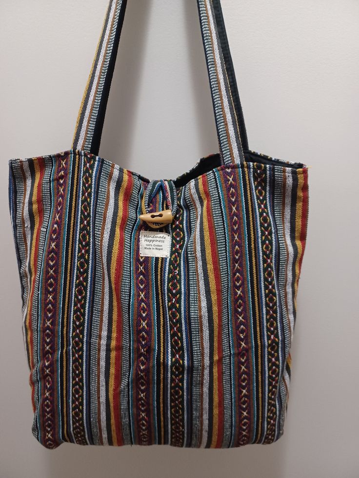 Simple, good-looking and durable bag that will last for years. This bag is 18 inches wide by nearly 18 inches tall, and it can accommodate a large volume of contents. The bag's exterior is made from woven cotton and the inside is lined with plain cotton.  The bag has an outside button closure and also an inside button closure. There is a pocket inside the bag.  All the steps of making the bag, from fiber processing, to spinning and weaving the yarn, are performed mainly by women. Cotton Tote Weekender Bag With Pockets, Rectangular Cotton Weekender Bag With Pockets, Cotton Double Handle Beach Bag For Everyday Use, Cotton Beach Bag With Double Handle For Daily Use, Cotton Beach Bag With Double Handle For Everyday Use, Cotton Weekender Bag With Adjustable Strap And Tote Shape, Cotton Weekender Bag With Adjustable Strap, Cotton Weekender Bag With Adjustable Strap For Daily Use, Rectangular Woven Canvas Bag For Daily Use