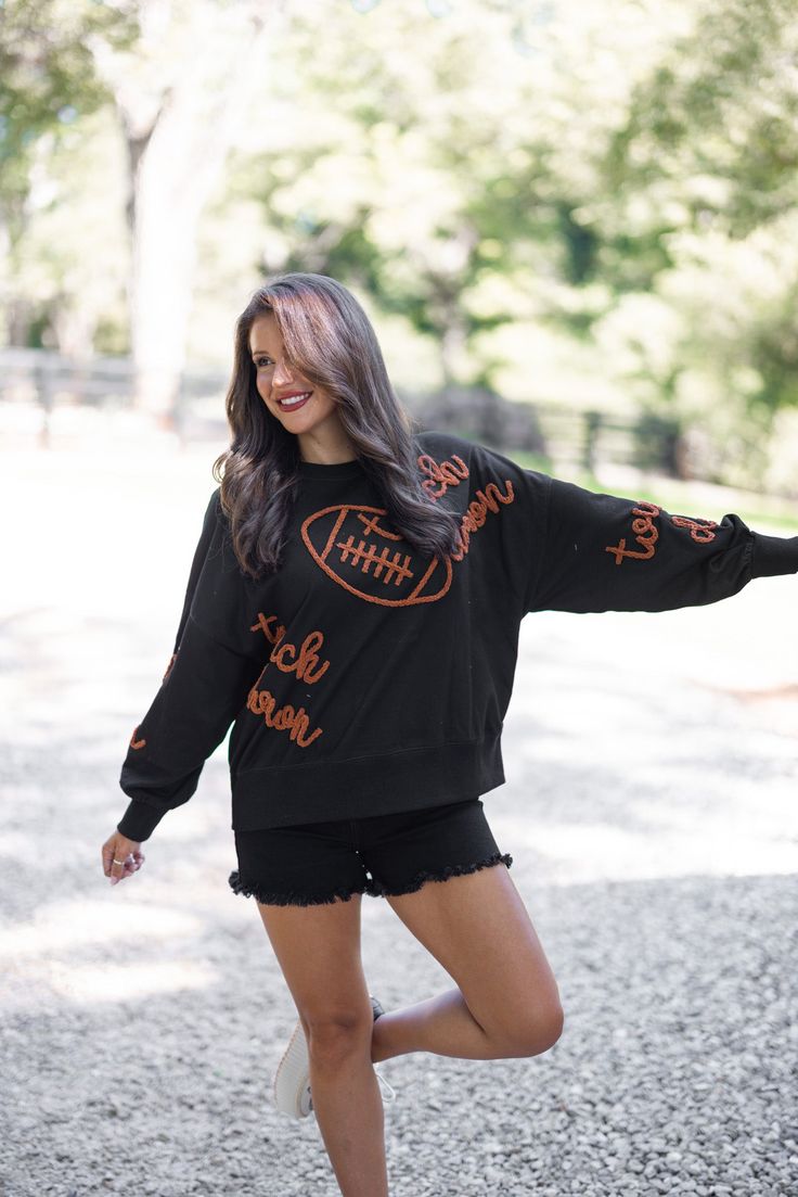 Black terry knit pullover accented with embroidered footballs and 'touchdown' In the Fall we are all Touchdown Obsessed!! Show your gameday spirit in this fabulous black sweatshirt, featuring brown embroidery braided footballs and the word 'touchdown' on the front and down the sleeves. With a crew neckline and long balloon sleeves, she's as comfy as she is festive. Tailgating never looked so stylish! True to size fit; relaxed silhouette Model is 5'5" wearing a small Fabric contains stretch Ribbe Football Party Outfit, Tailgating Outfits, Brown Embroidery, Tailgate Outfit, Football Sweatshirt, Graphic Tee Dress, Football Party, Vintage Couture, Black Sweatshirt