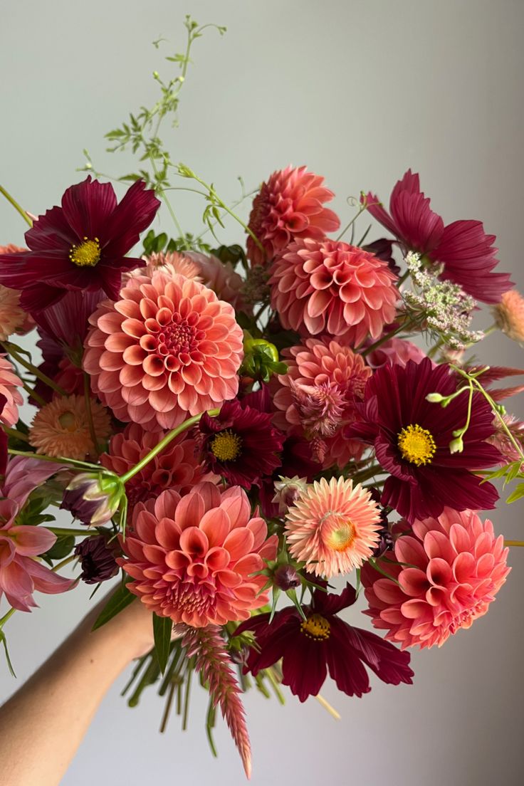 a person holding a bouquet of flowers in their hand with the other hand on it