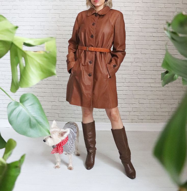 ➳ Gorgeous Danier Leather designer trench jacket ➳ Warm, caramel brown leather ➳ Ultra soft and buttery texture with a comfy fit ➳ Hidden inner chest pocket ➳ Belt loops at side ➳ Button down front closures ➳ Fully lined ➳ Jacket did not come with a belt, just belt loops. We included a 1970's tooled leather belt as it looks great styled with the coat      but the belt is interchangeable or looks great without a belt, if desired.  ➳ Dry cleaned, leather treated and ready to wear  Measurements   L Brown Long Coat With Buttons, Brown Outerwear With Flap Pockets And Lapel Collar, Business Brown Outerwear With Flap Pockets, Brown Business Outerwear With Flap Pockets, Leather Long Coat For Fall, Brown Workwear Outerwear With Flap Pockets, Brown Leather Outerwear For Work, Fitted Outerwear With Leather Lining For Fall, Brown Leather Jacket With Flap Pockets For Business