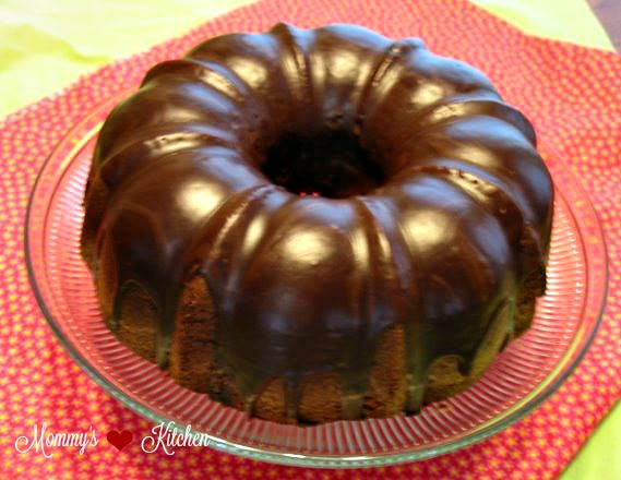 a chocolate bundt cake sitting on top of a red table cloth next to a glass plate