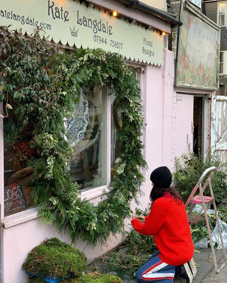 a woman in red jacket next to window with wreath on it