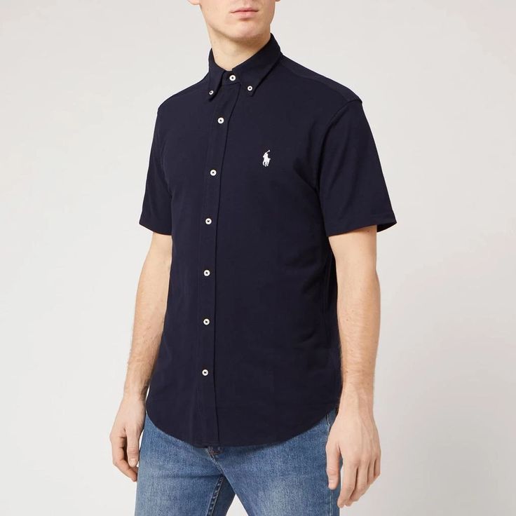 This navy short-sleeved shirt by Polo Ralph Lauren is detailed with a buttoned collar and a central placket with contrasting white buttons. The forever investment is completed with an embroidered polo player logo on the chest. Navy Short Sleeve Polo Shirt For Work, Short Sleeve Polo Shirt For Work, Short Sleeve Polo Shirt With Placket For Work, Classic Collared Short Sleeve Shirt With Button Closure, Short Sleeve Polo Shirt With Button Closure For Work, Classic Navy Cotton Short Sleeve Shirt, Casual Short Sleeve Polo Shirt With Buttons, Navy Short Sleeve Tops With Button Closure, Classic Cotton Short Sleeve Shirt With Snap Buttons