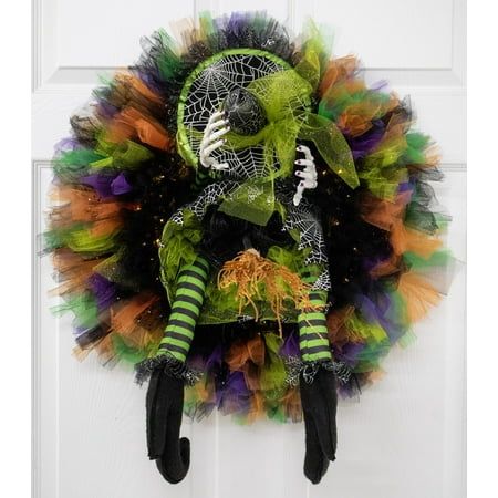 a halloween wreath hanging on a door with green and orange decorations, black gloves and striped socks