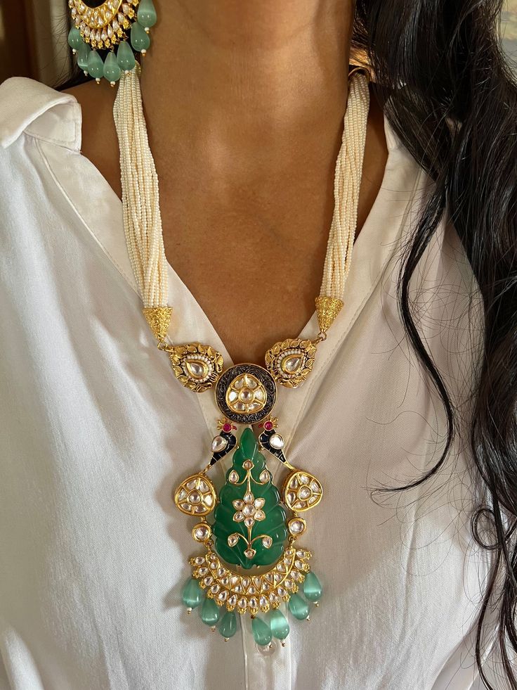 New Arrival ♥️ All our pieces are in stock and will be dispatched with in 24 to 48 hours of order. Orders received during the weekend will be dispatched on Monday.  Beautiful carved stone at the center adds perfect glamour. One of our favorite picks for the wedding season ❤️ Materials: Siver, Gold, Brass, Copper, Jade Stone, Mini Pearls, Kundan Work Dimensions Weight of the necklace: 110 grams Drop Length of the necklace: 10.5 inches Height of pendant: 5.5 inches Width of pendant: 3 inches Weight of earrings is 60 g per pair. (Heavier Side) Length of earrings: 9 cms. Width of earrings: 6 cms. Push back closure/ Omega Clip at the back. Necklace has hook closure and is adjustable. Luxury Kundan Pendant Necklace Gift, Elegant Bridal Necklace With Tilla Pendant, Traditional Jewelry Sets With 17 Jewels Pendant, Fusion Kundan Pendant Jewelry, Fusion Style Kundan Pendant Jewelry, Unique Chandbali Jewelry With Intricate Design, Handmade Temple Jewelry For Wedding, Fusion Style Wedding Pendant Necklace, White Necklace With Peacock Design For Gift