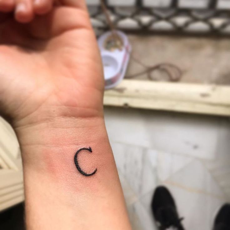 a small wrist tattoo with the letter c on it