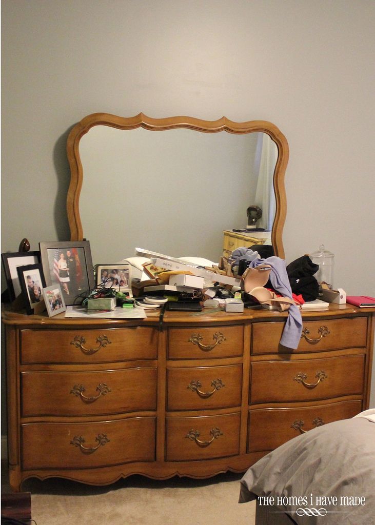 a bedroom with a dresser, mirror and pictures on it