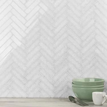 a table topped with plates and cups next to a white brick wall covered in herringbone tiles