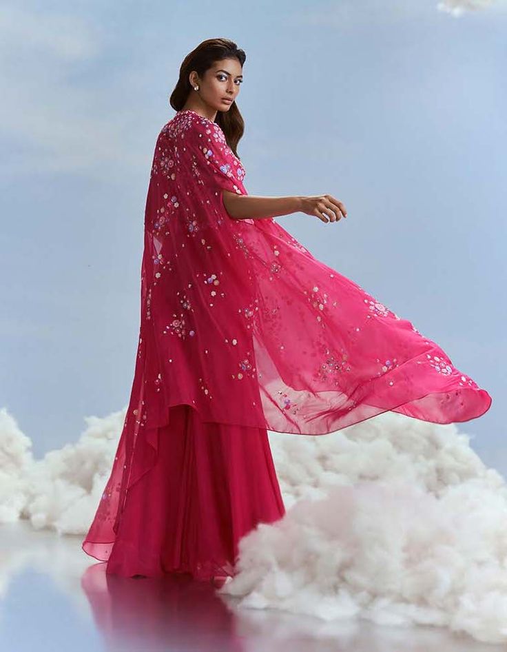 Elevate your style with the izmir cape, crop top, and kalidar sharara ensemble. The chiffon cape adds a touch of ethereal grace, while the crop top crafted from organza with tussar lining exudes sophistication. Paired with georgette kalidar sharara featuring shantung lining, this ensemble seamlessly combines elegance with modern flair. Step into refined charm with this meticulously designed set, perfect for a distinctive and graceful appearance. Chiffon Cape, Beaded Neckline, Sharara Set, Top Crafts, Fuchsia Pink, Indian Design, Handmade Clothes, Flared Sleeves, Aza Fashion