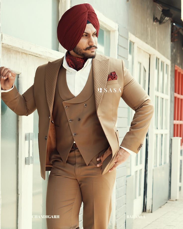 a man in a turban is leaning against a wall with his hands on his hips