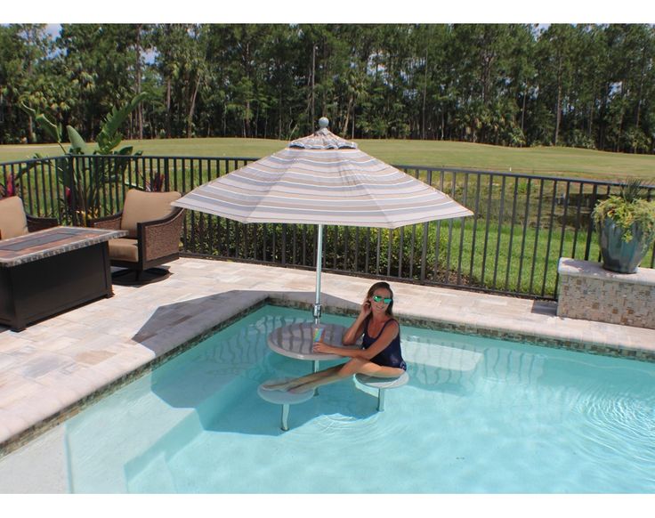 a woman sitting in the middle of a swimming pool with an umbrella over her head