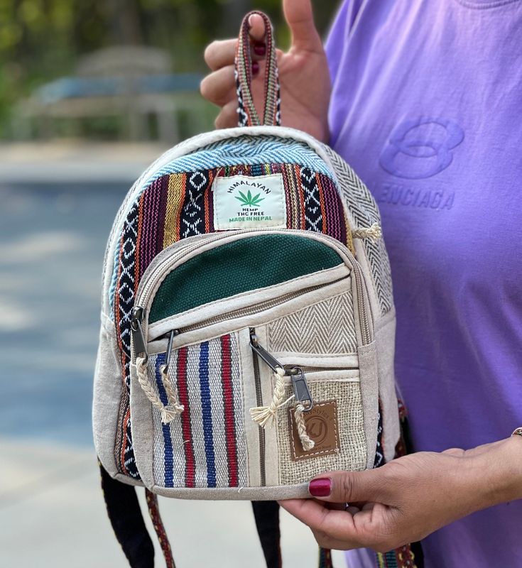 a woman is holding a small backpack in her hand