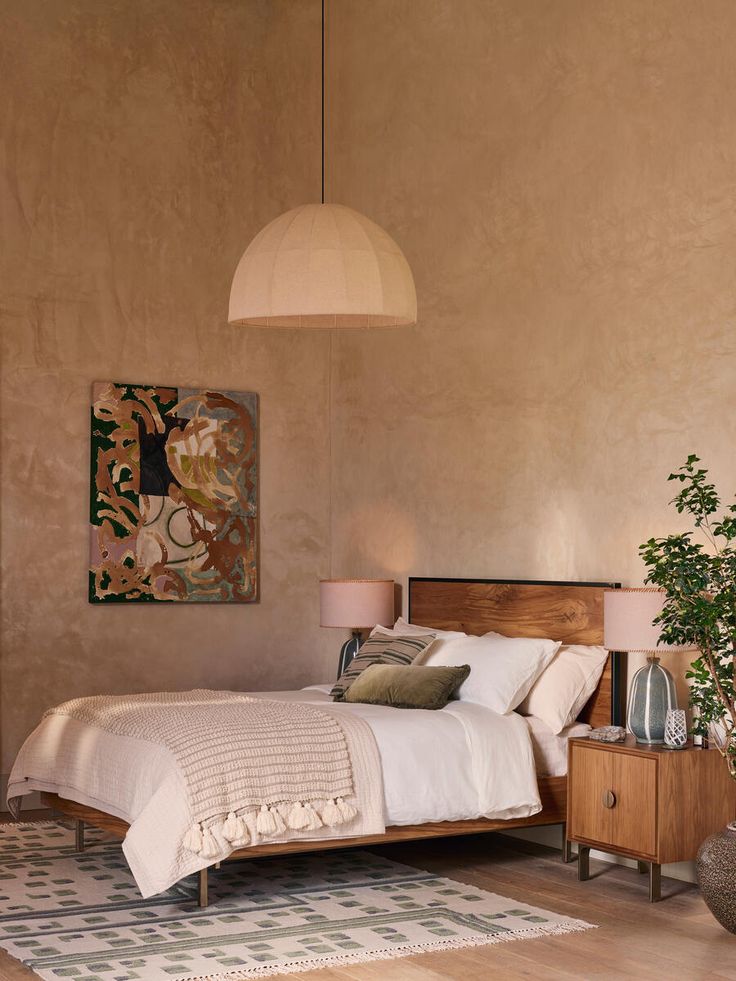 a bed sitting in a bedroom next to a lamp and a painting on the wall