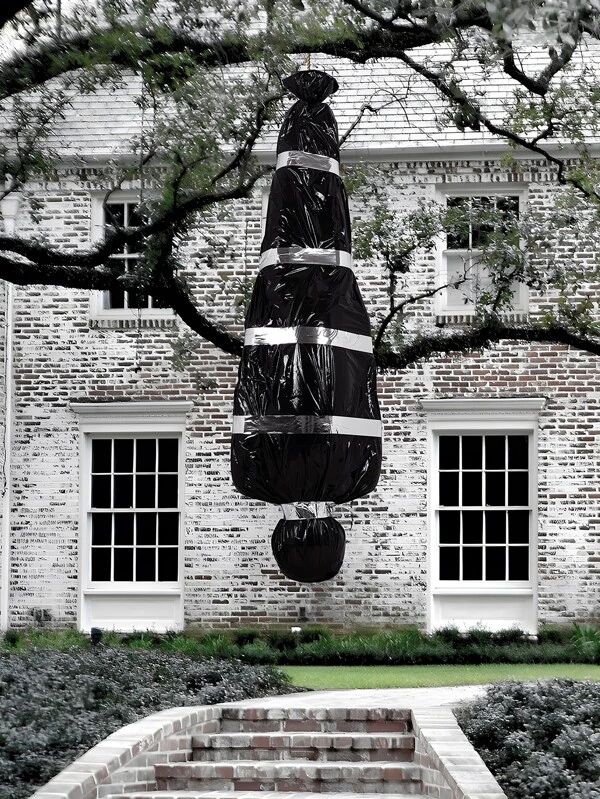 a large black sculpture sitting in front of a brick building