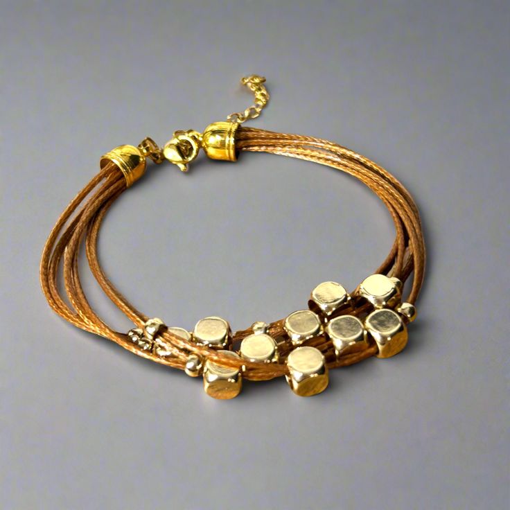 Get ready to elevate your wrist game with this multi-strand leather bracelet. Featuring gold-plated floating beads and a lobster clasp closure, this timeless piece is the perfect way to add a touch of sophistication to any outfit. Length: 6.5" + 1.5" extender chain Lobster clasp closure - for a secure fit 6 strands of brown leather - for the perfect boho vibe 18K PVD Gold plated stainless steel - long lasting plating and hypoallergenic Handmade in China - to bring you the best possible price Thi Adjustable Double Strand Gold-tone Jewelry, Chic Multi-strand Metal Jewelry, Adjustable Gold Bracelets For Accessorizing, Adjustable Gold Leather Bracelet Chic Style, Adjustable Gold Leather Chic Bracelet, Gold Adjustable Double Strand Beaded Bracelets, Adjustable Gold Leather Bracelet, Adjustable Gold Beaded Metal Bracelets, Adjustable Gold-tone Metal Beaded Bracelet