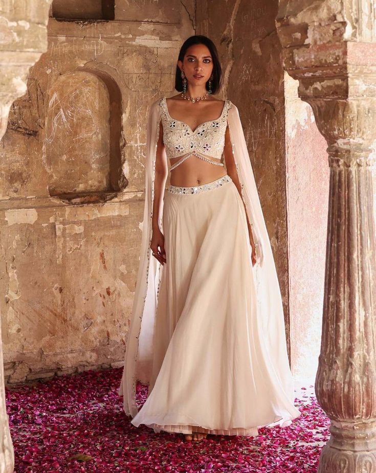 Indulge in sophistication with this embellished choli featuring attached flared sleeves, perfectly paired with a circular skirt adorned with an embellished belt and can-can detailing. This ensemble epitomizes elegance, offering a seamless blend of traditional charm and contemporary flair. Make a statement at any event or celebration with this exquisite outfit that exudes grace and style. Circular Skirt, Ivory Blouse, Embellished Belt, Night Court, Can Can, Traditional Wear, Modern Fashion, Flared Sleeves, Indian Outfits