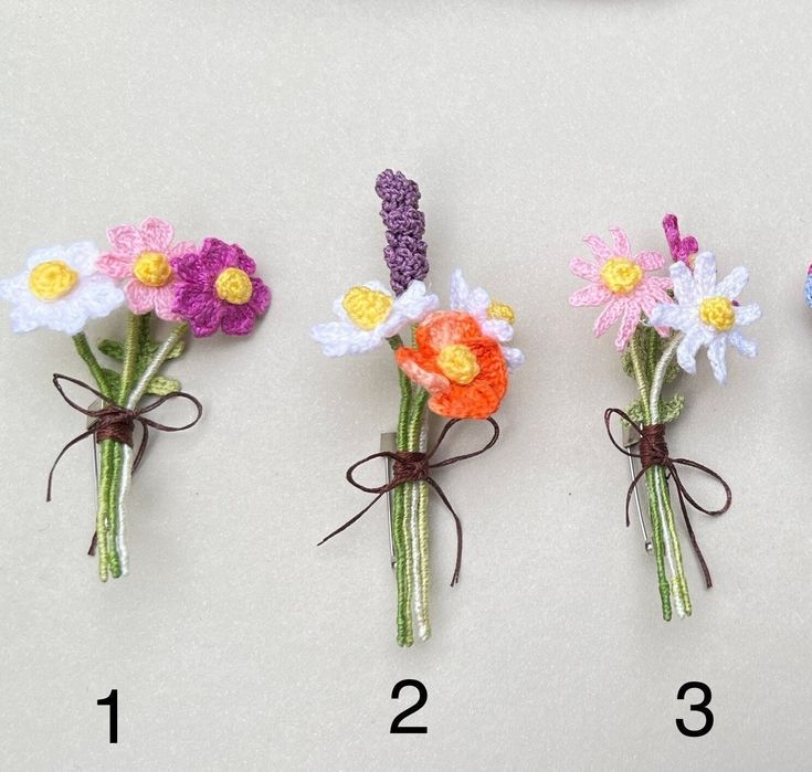 four crocheted flowers tied together in different colors and sizes, each with a ribbon