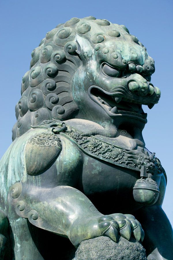 a statue of a lion holding a bell in its paws and sitting on it's hind legs