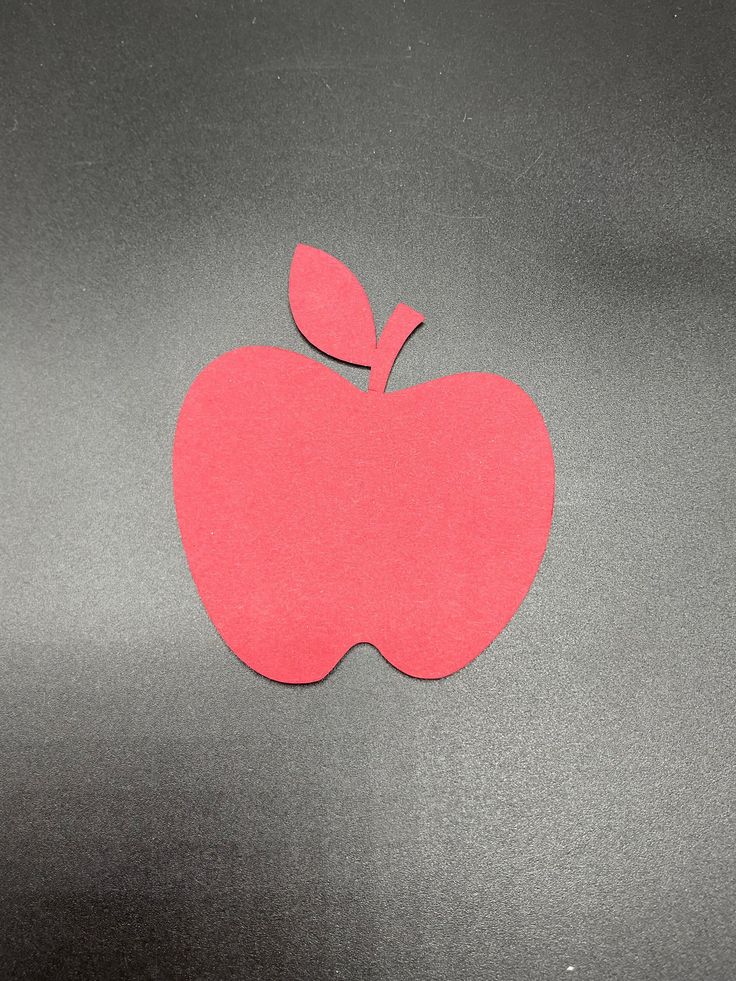 an apple cut out on top of a metal surface with a red piece of paper sticking out of it