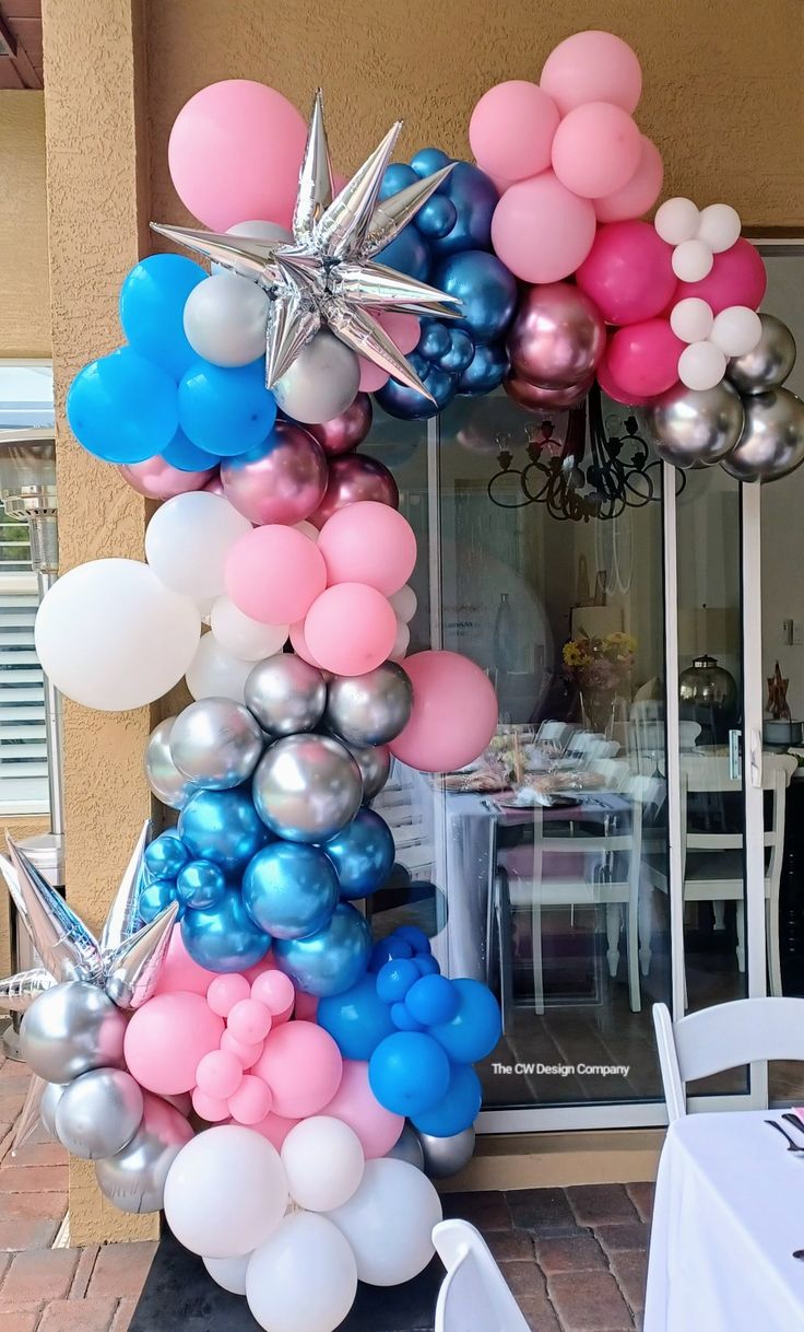 the balloon arch is decorated with stars and pink, blue, and silver balloons for a birthday party