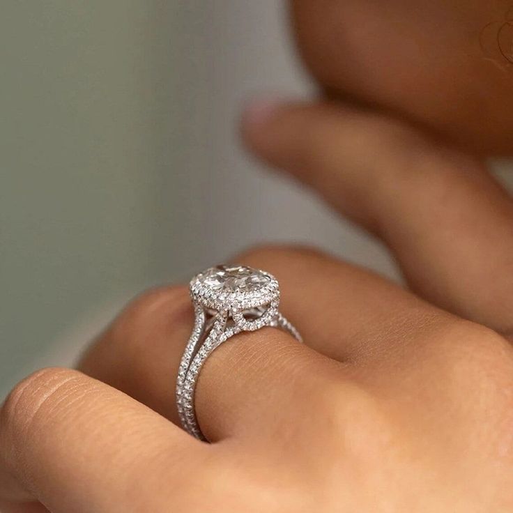 a close up of a person's hand with a diamond ring on their finger