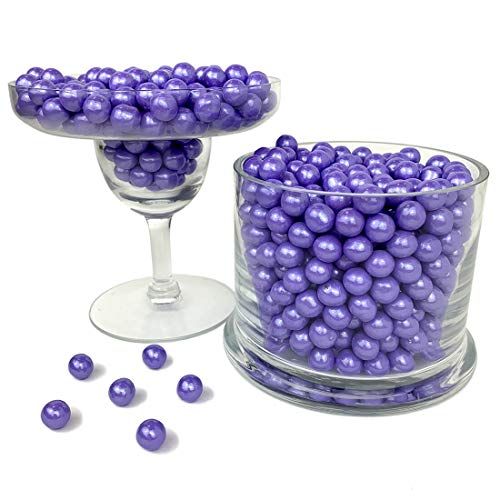 purple balls in a glass vase next to some wine glasses