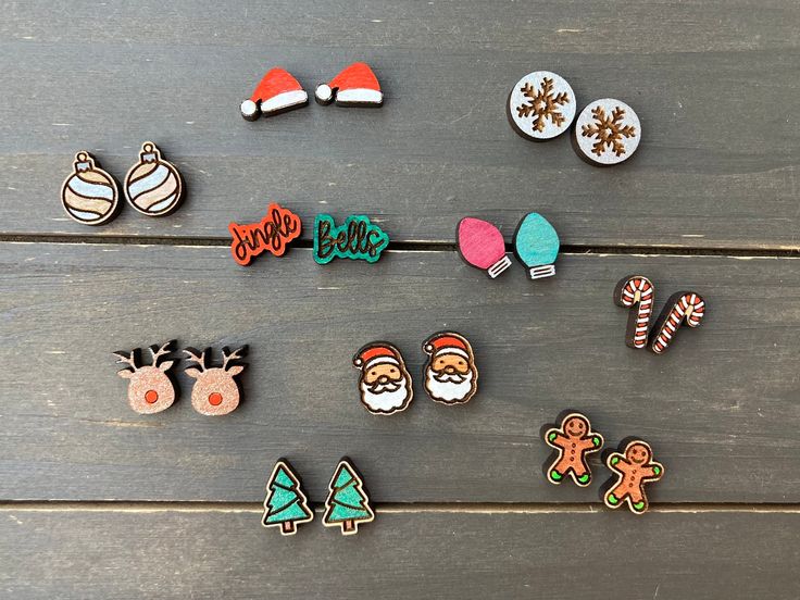 several christmas themed pins and magnets on a wooden surface