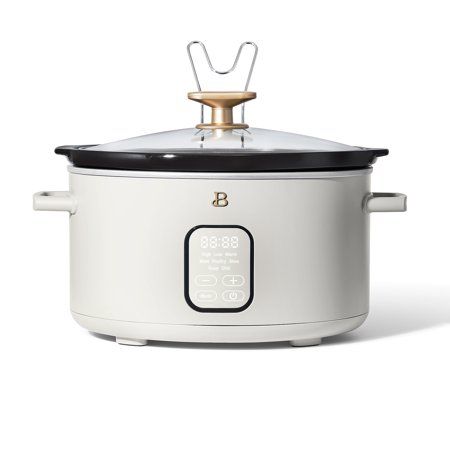 an electric crock pot with the lid open on a white background, with a gold handle