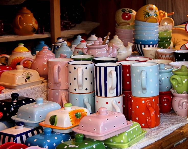 there are many colorful cups and dishes on the table with polka dot designs in them