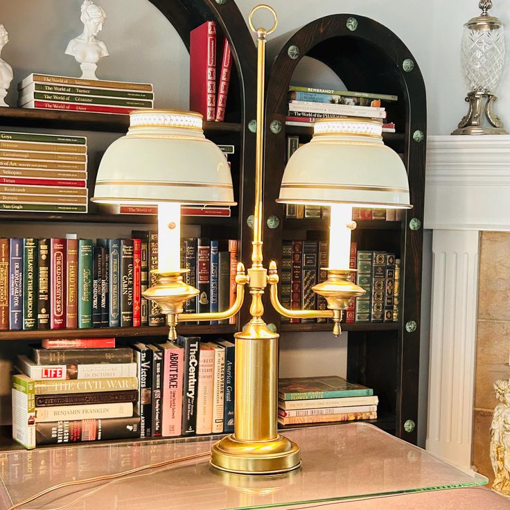 two lamps sitting on top of a table in front of a book shelf filled with books